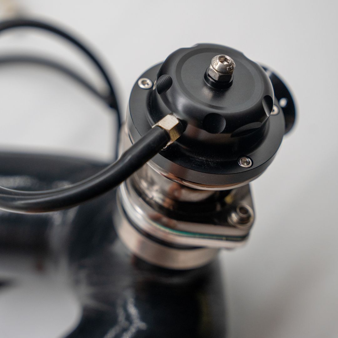 Close-up of a mechanical component with a black cable on a reflective surface